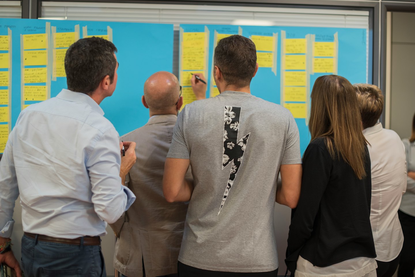 Diverse professionals brainstorm ideas on sticky notes.